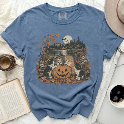 Four kittens sit around a jack-o'-lantern on a blue t-shirt graphic.