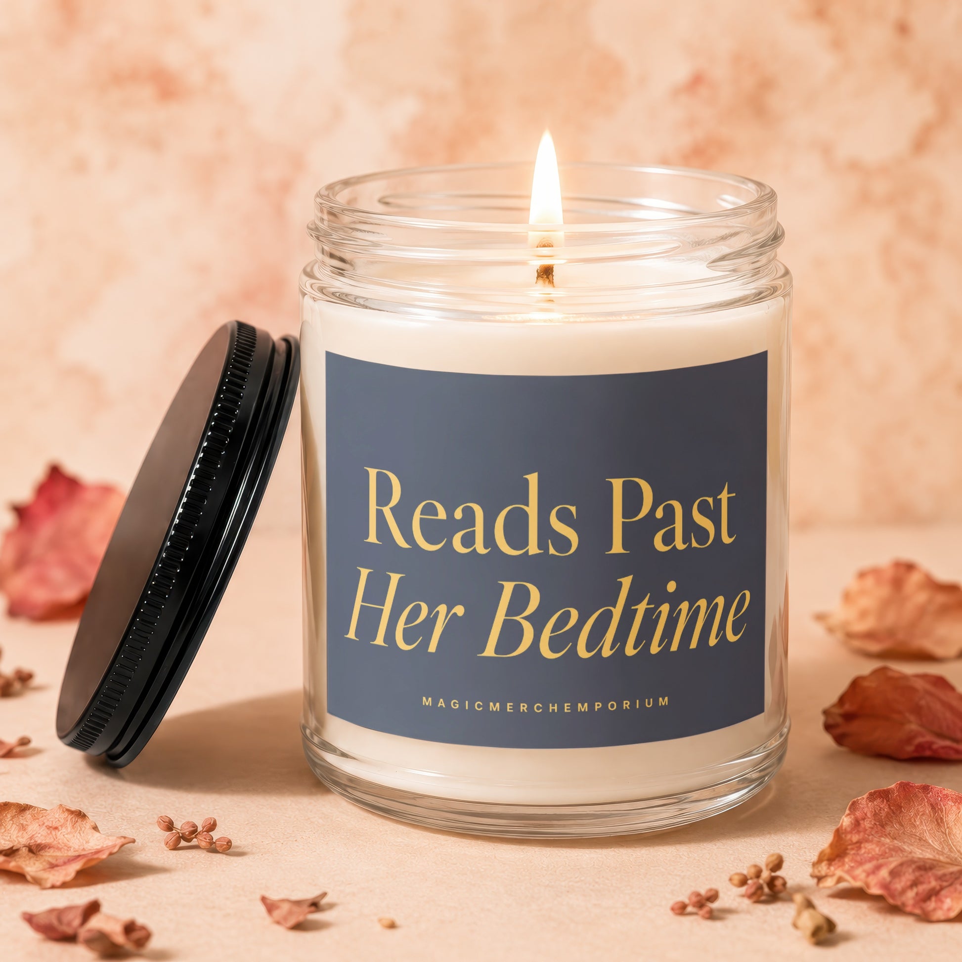 Glass jar candle with lit flame and label that reads "Reads Past Her Bedtime".