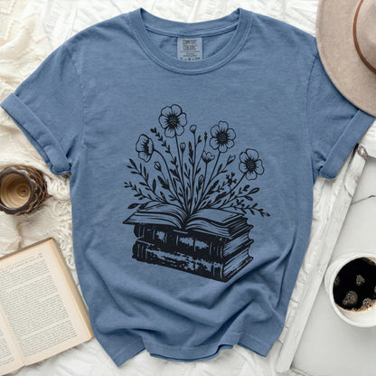 Blue t-shirt with black illustration of an open book with flowers growing from it.