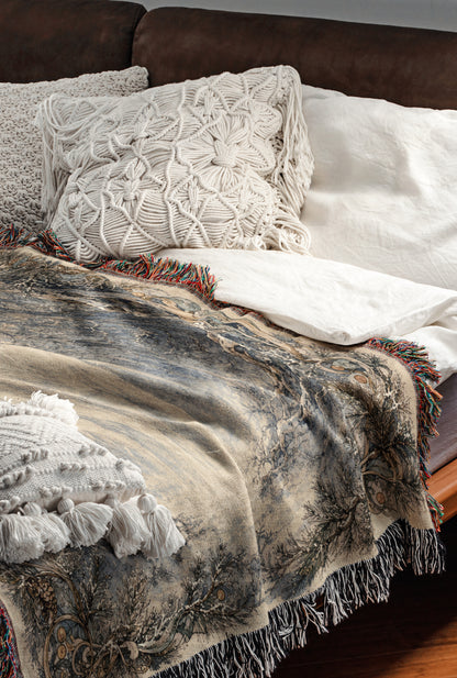 a cozy and inviting bedroom scene, featuring a bed with a white comforter and a decorative throw blanket with a floral pattern. The bed is adorned with two white pillows and a single throw blanket with fringe details. The overall color scheme of the room is neutral, with the white elements providing a sense of calm and tranquility.