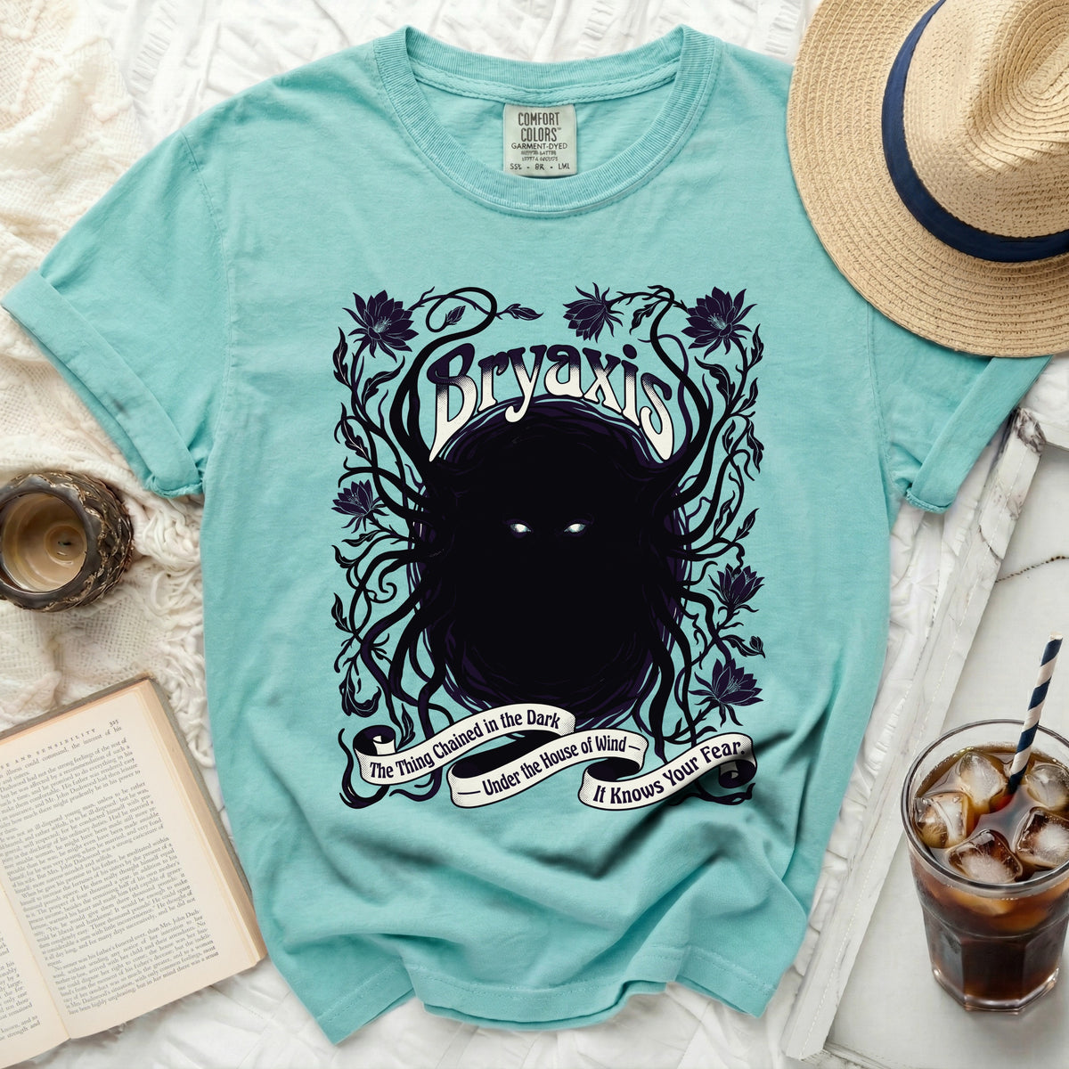 Bryaxis shirt with dark floral and creature design and text.
