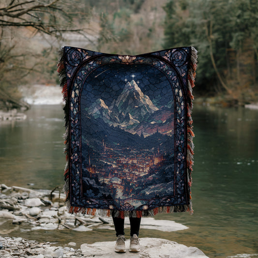 A person stands on a rock, holding a large, intricately designed tapestry that depicts a mountainous landscape with a city in the foreground.