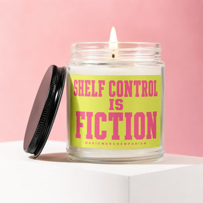 Glass candle with lit wick and black lid, reads "Shelf Control Is Fiction" in pink.