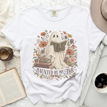 Ghost reading a book surrounded by flowers with text "Haunted by my TBR".