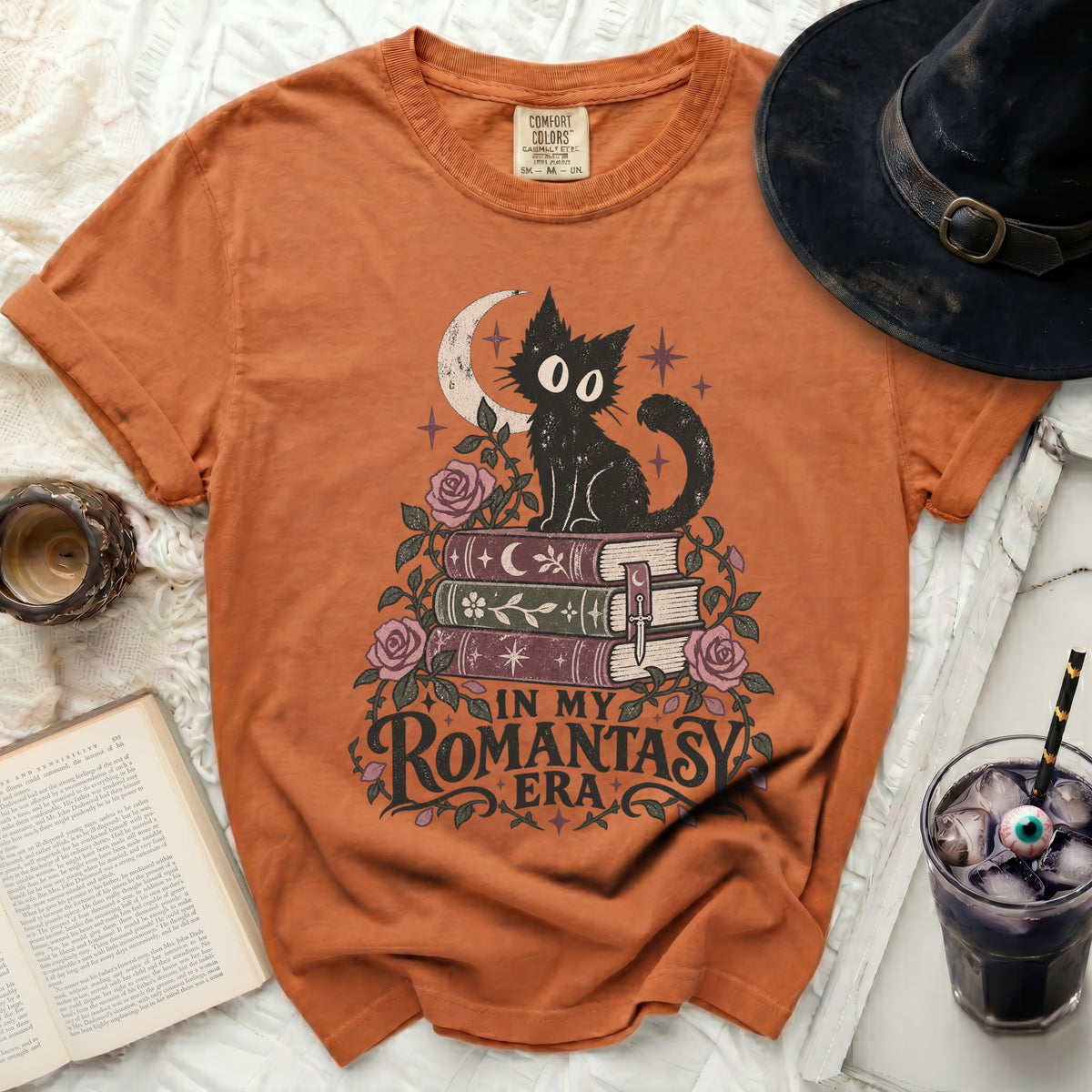 Orange t-shirt with black cat on books, crescent moon, stars, and text "In My Romantasy Era".