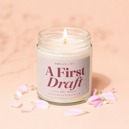 Jar candle with lit wick, label reads "A First Draft".