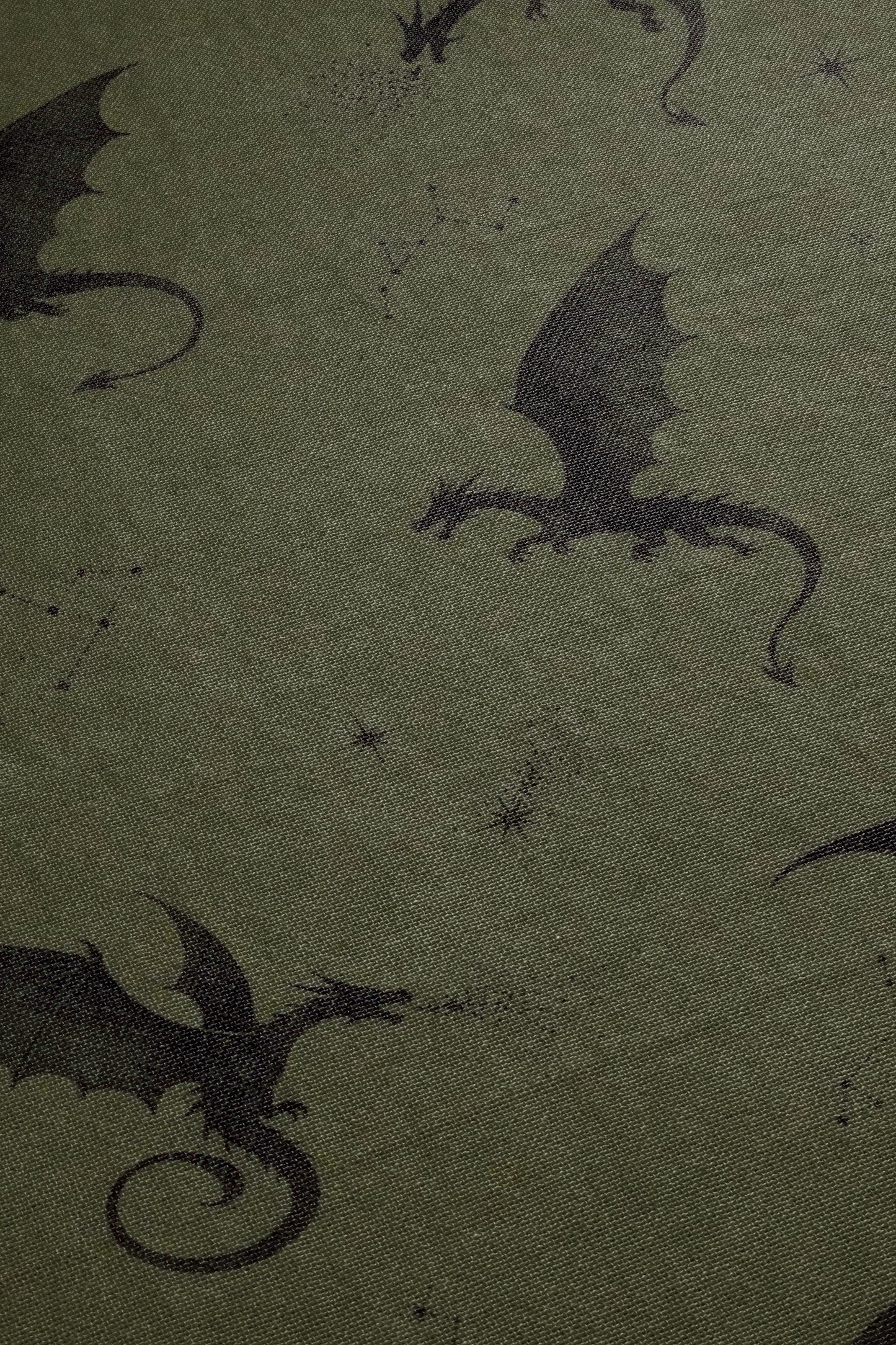 a close-up view of a dark green fabric with a repeating pattern of black silhouettes of dragons.