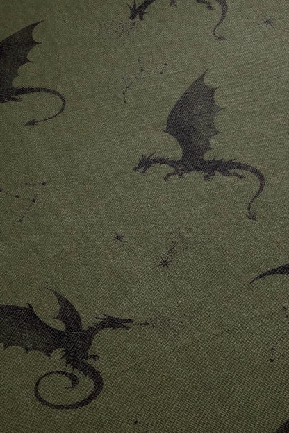 a close-up view of a dark green fabric with a repeating pattern of black silhouettes of dragons.