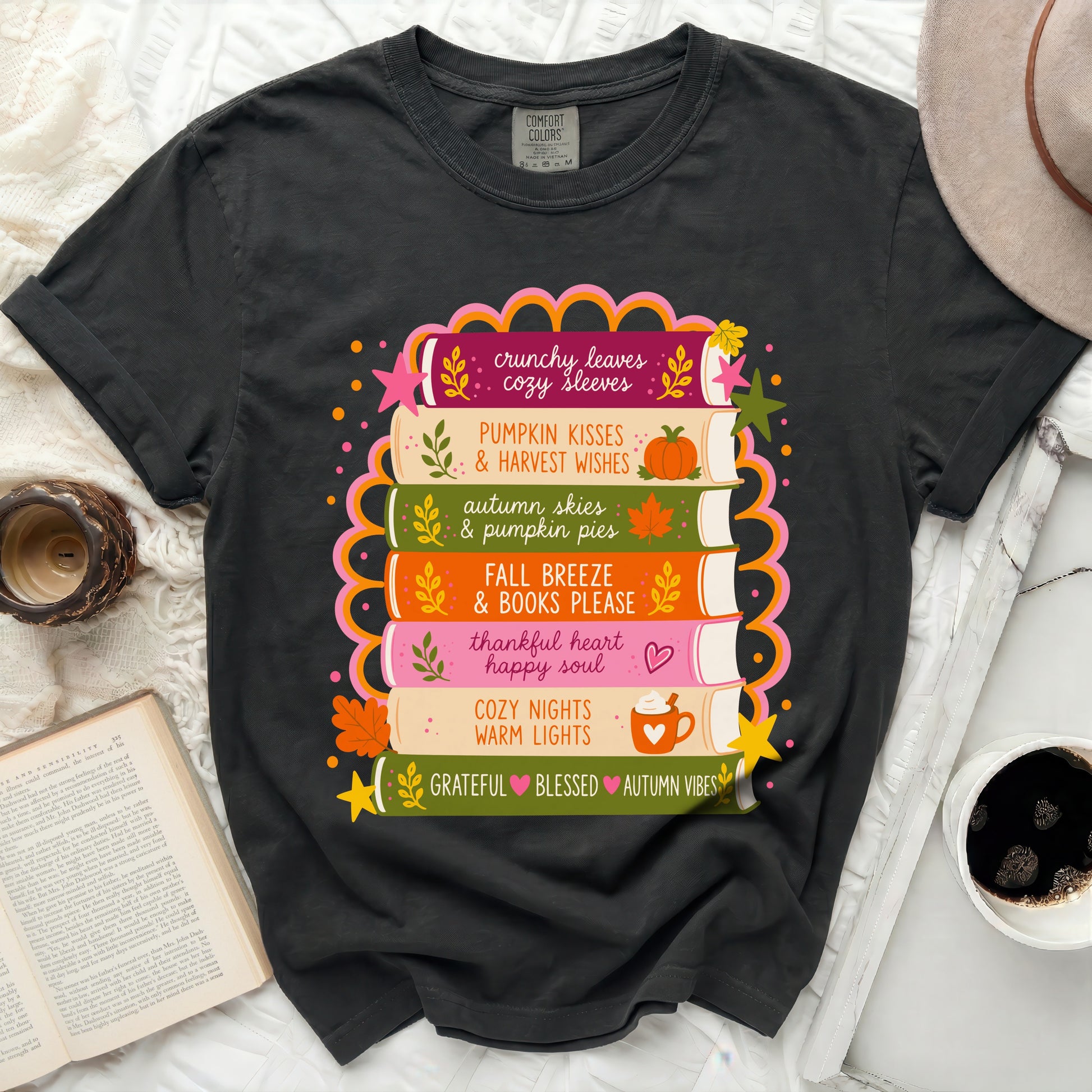 Black t-shirt with stack of books featuring fall phrases and illustrations.