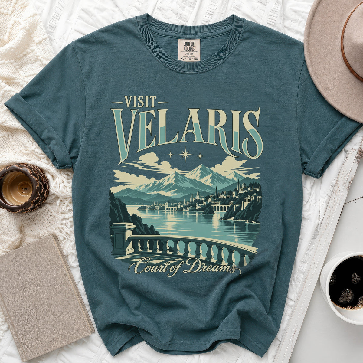 Teal t-shirt with "Visit Velaris Court of Dreams" graphic and mountainous city scene.