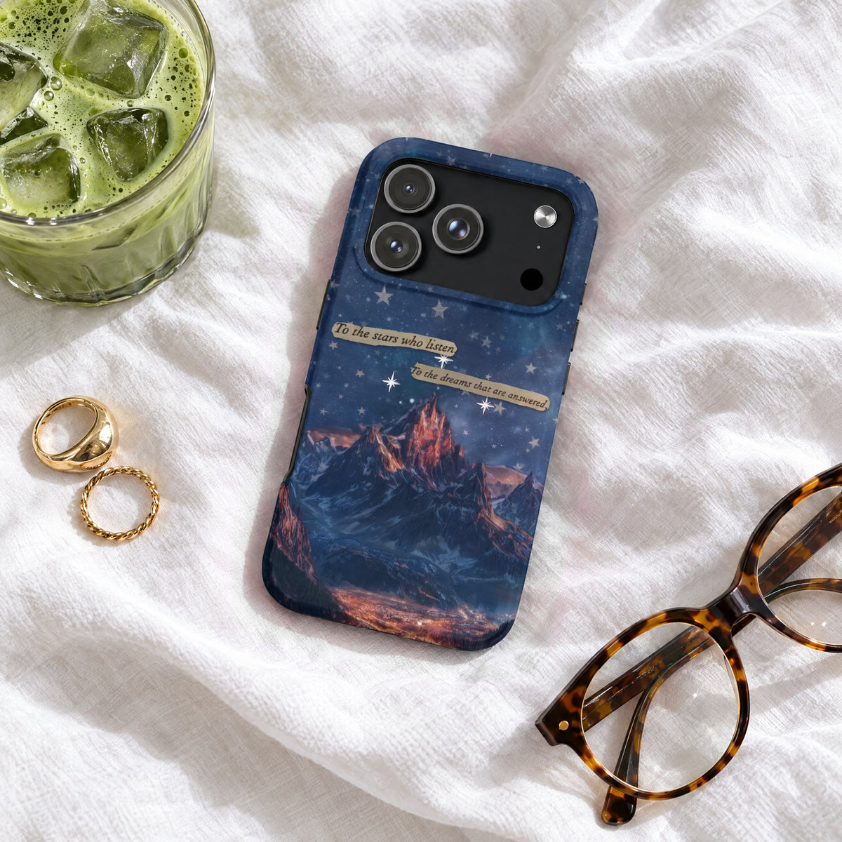 Blue mountain-themed phone case with starry night design and text accents on white linen fabric.