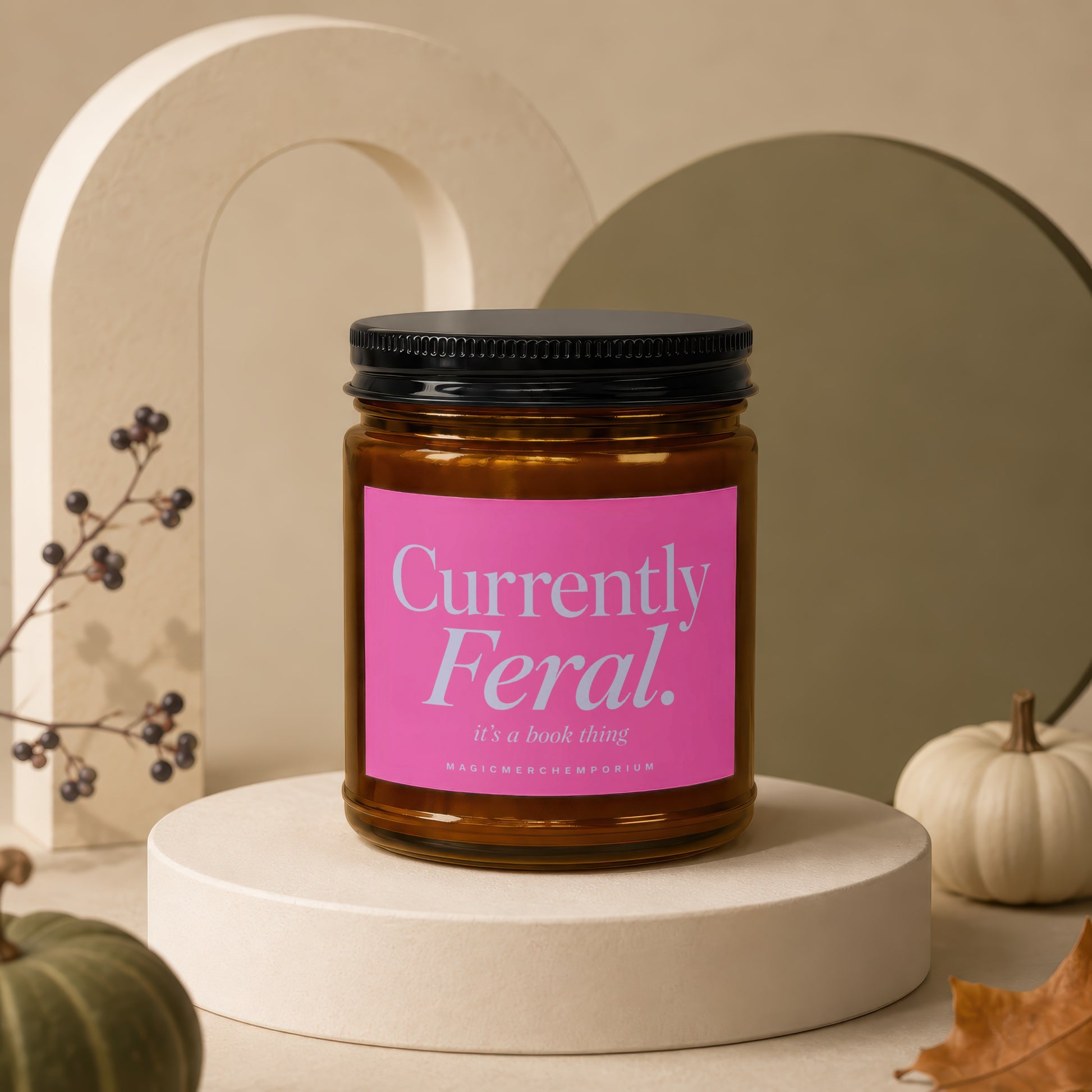 Brown glass jar candle with pink label reading "Currently Feral. it's a book thing".