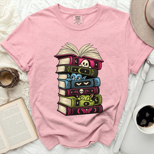 Pink t-shirt with a graphic of stacked books featuring Halloween characters.