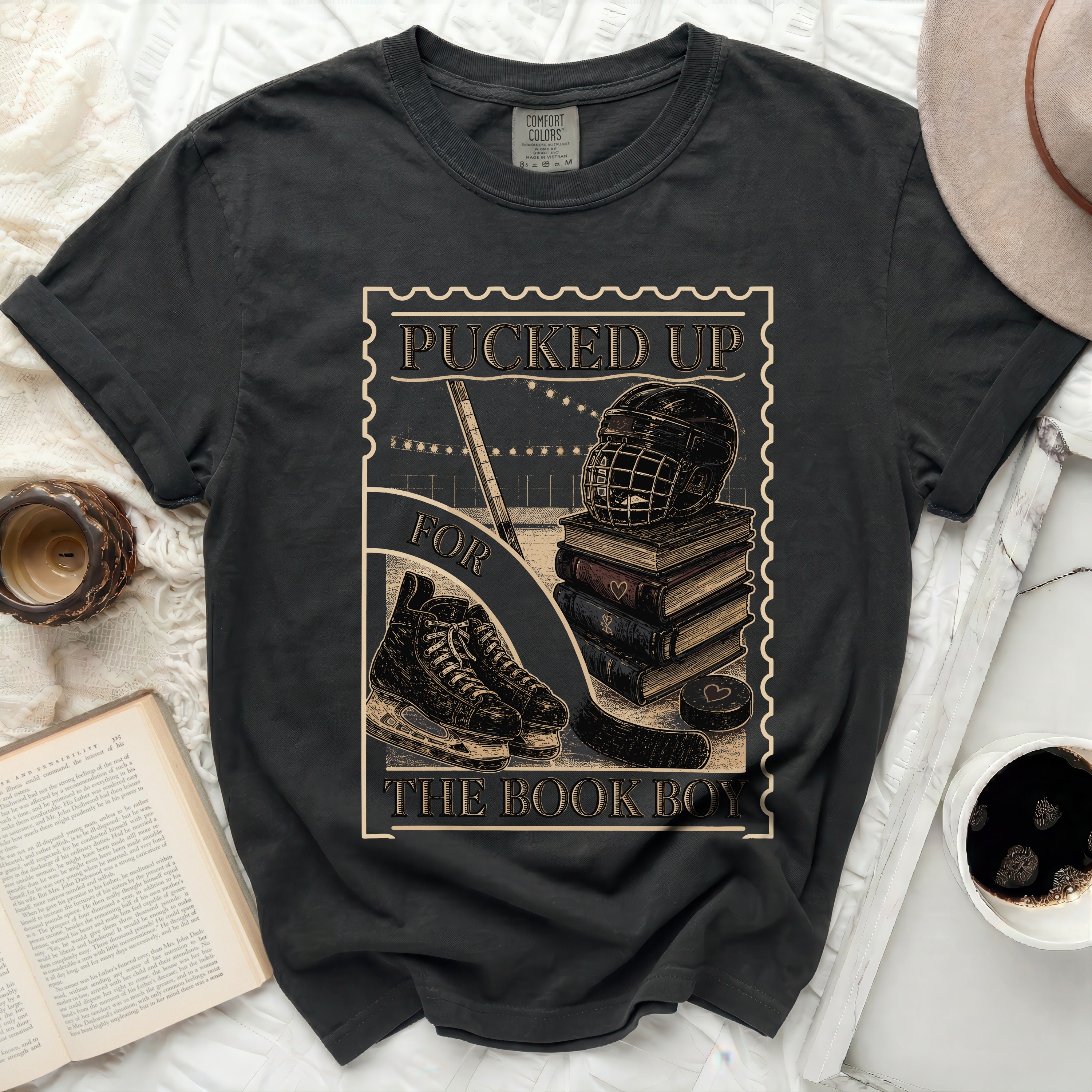 T-shirt graphic with hockey puck, skates, helmet, and stacked books.