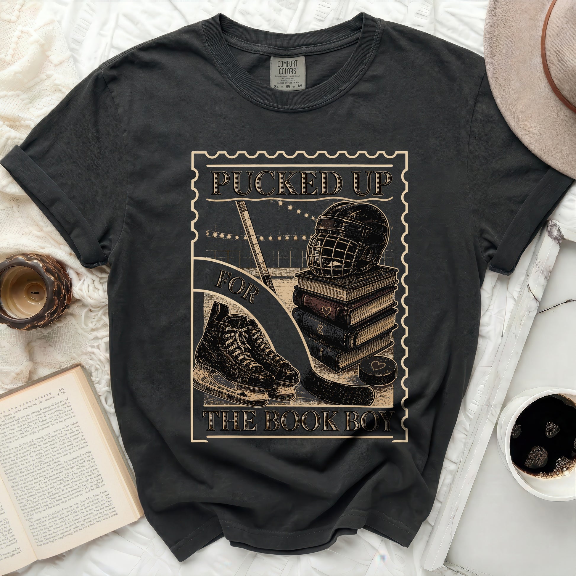 T-shirt graphic with hockey puck, skates, helmet, and stacked books.