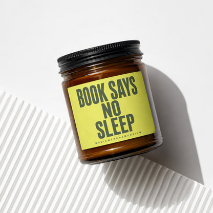 Amber glass candle with yellow label reading "BOOK SAYS NO SLEEP MAGICMERCHEMPORIUM".