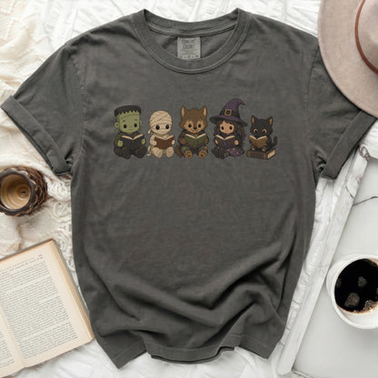 T-shirt with cartoon characters Frankenstein, mummy, werewolf, witch, and cat reading books.