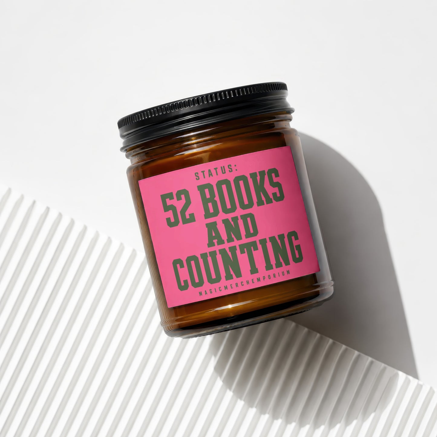 Glass jar candle with pink label reading "Status: 52 Books and Counting".