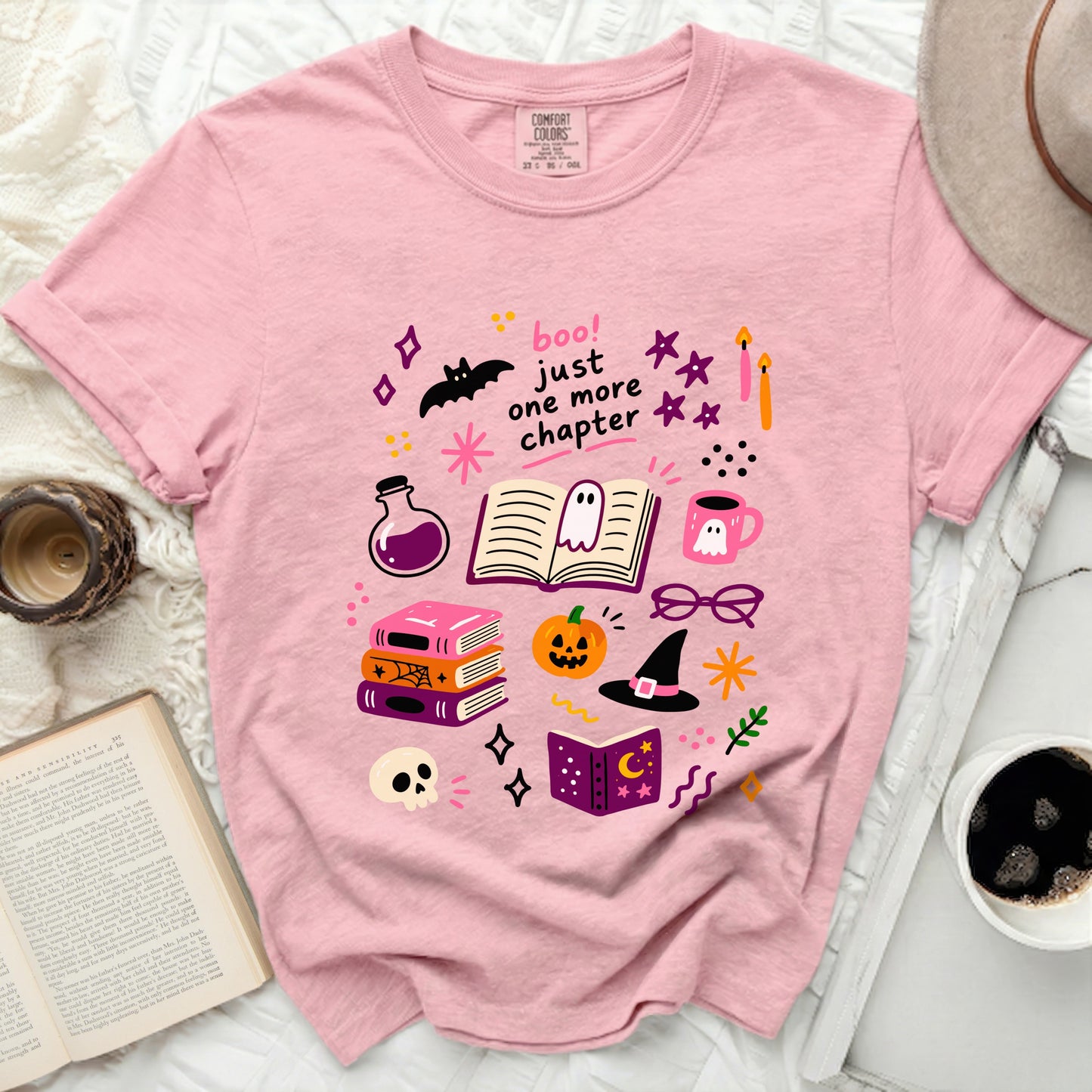 Pink t-shirt with Halloween book-themed illustrations and "Boo! Just one more chapter" text.