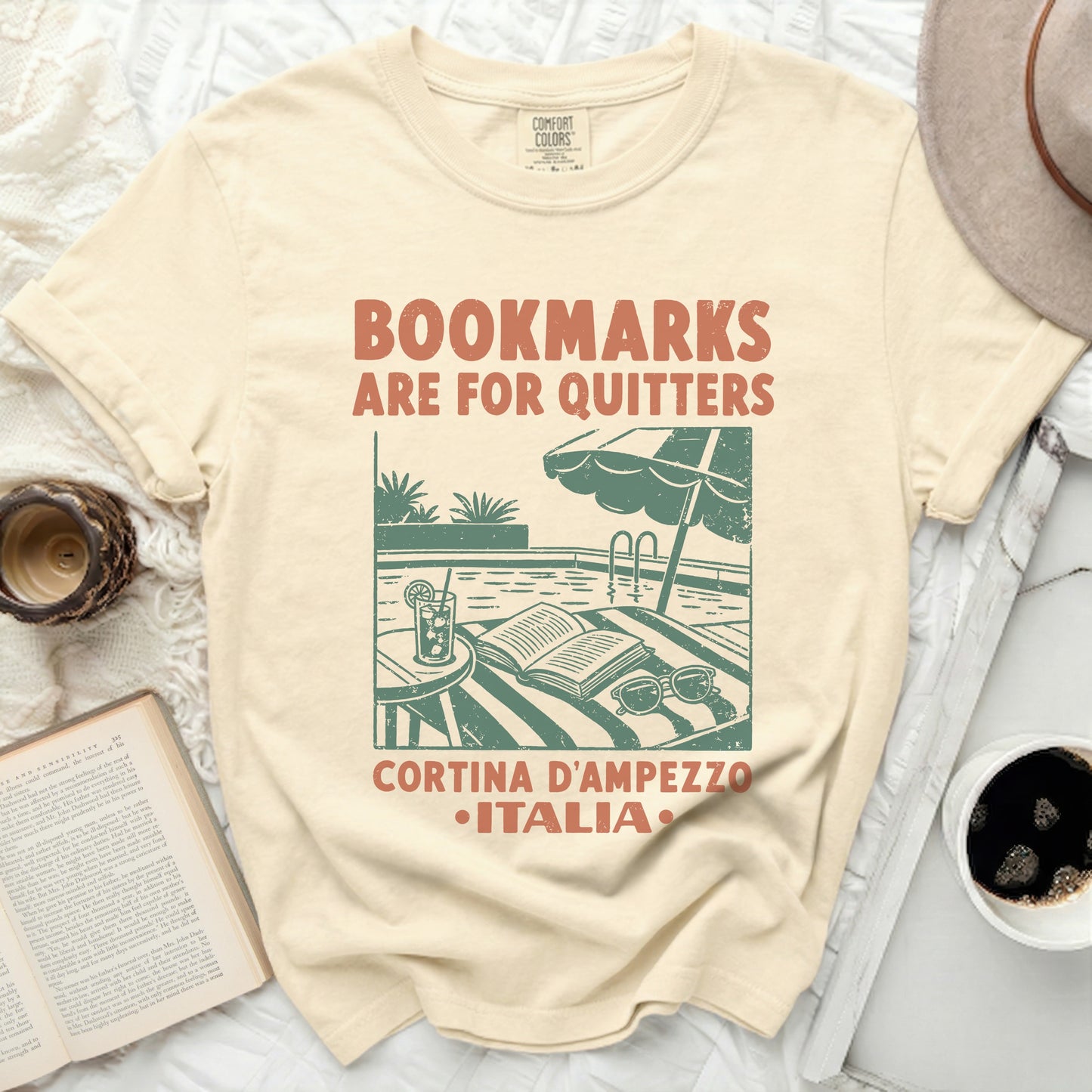 Cream t-shirt with "Bookmarked are for quitters" and Italy vacation graphic.