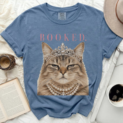 Fuzzy cat wearing a crown and pearl necklace with "BOOKED." text.