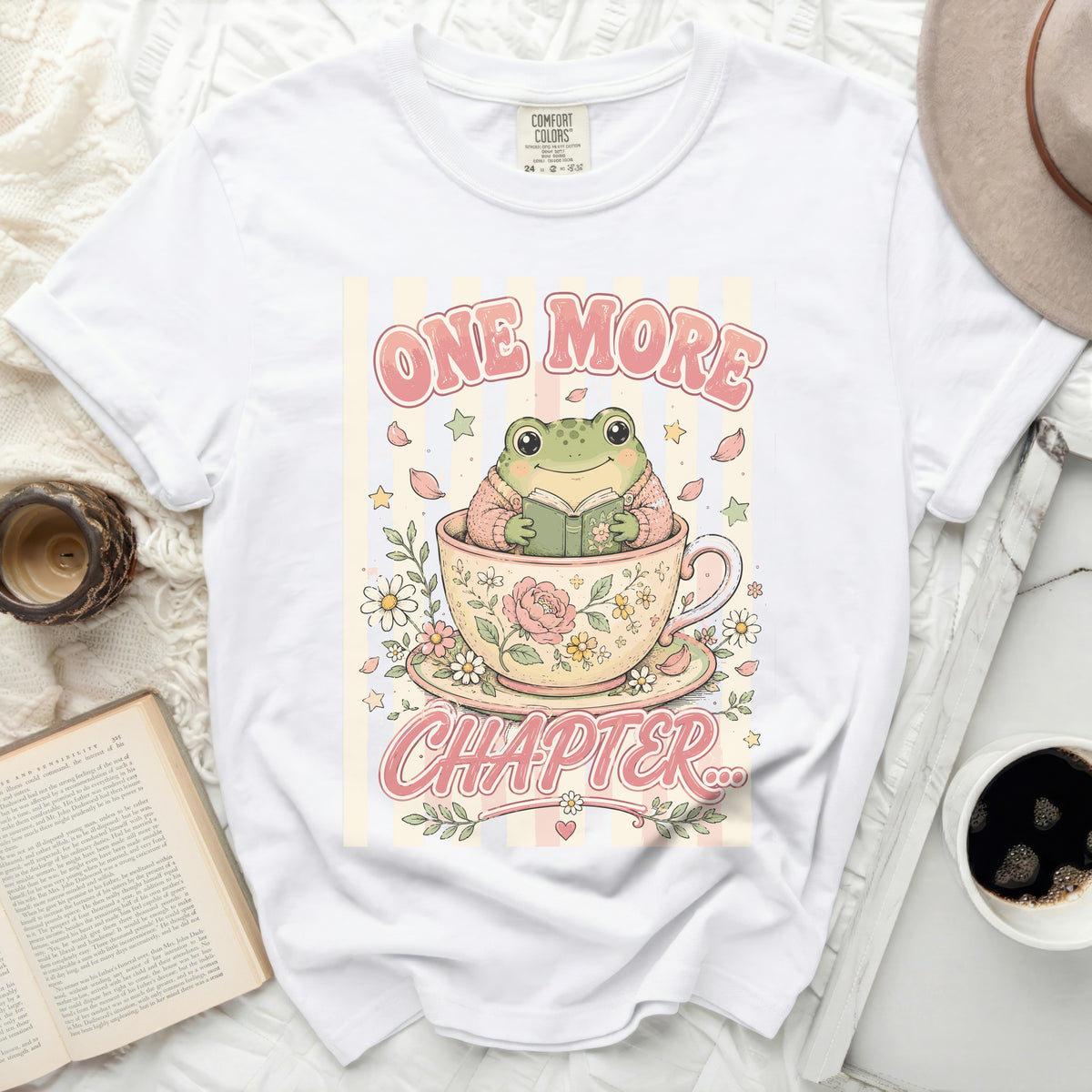 T-shirt with a cute frog reading a book in a teacup, text "ONE MORE CHAPTER".