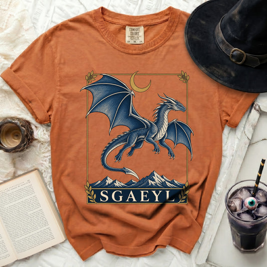 Orange t-shirt with a blue dragon, moon, and mountains graphic labeled "SGAEYL".