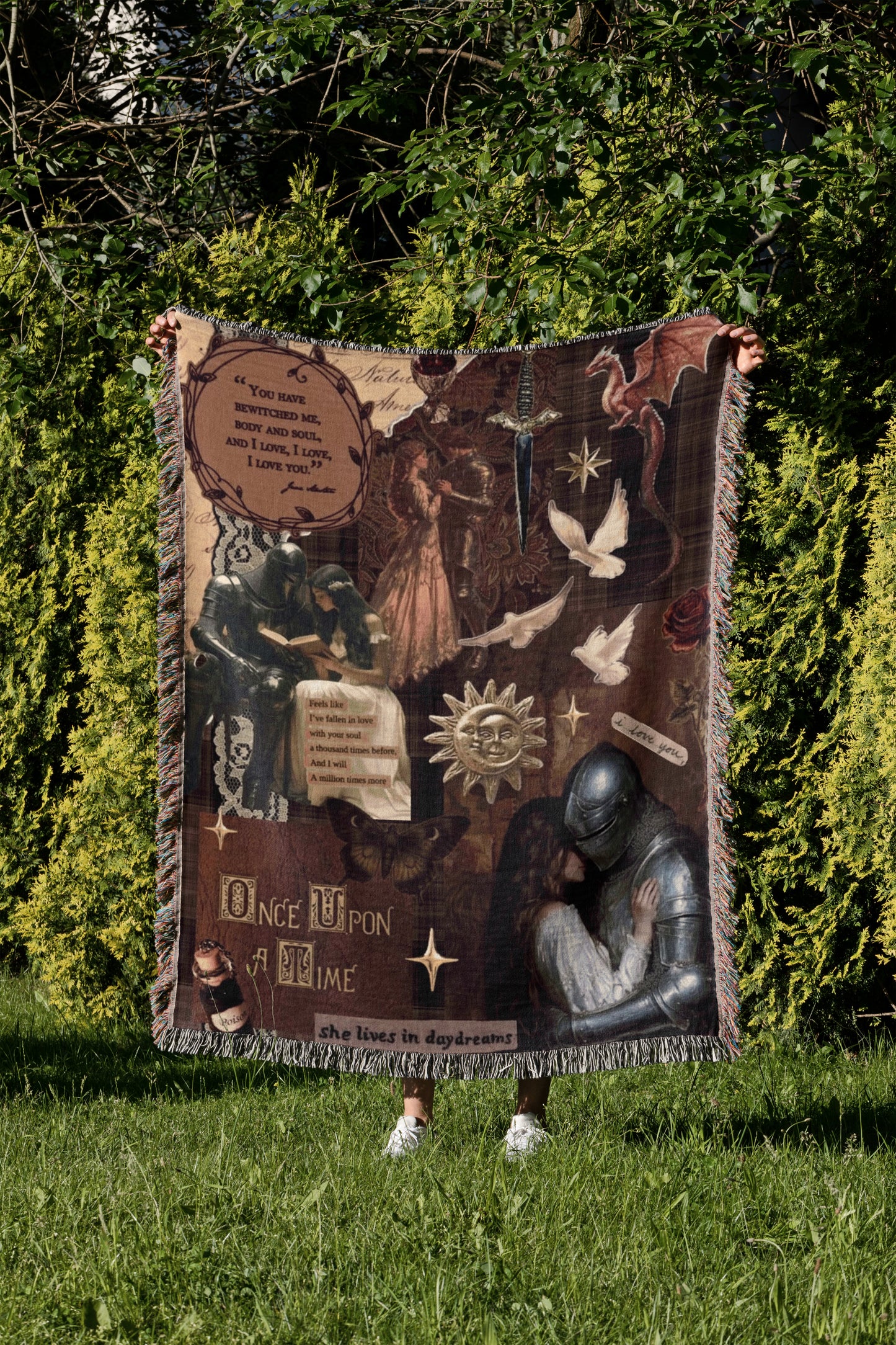 a person standing in a grassy area, holding a large blanket that is decorated with various images and text.