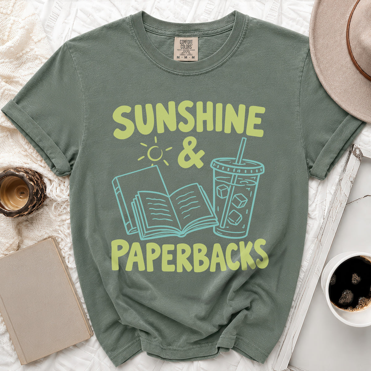 Sage green t-shirt with "Sunshine & Paperbacks" text and book graphics.