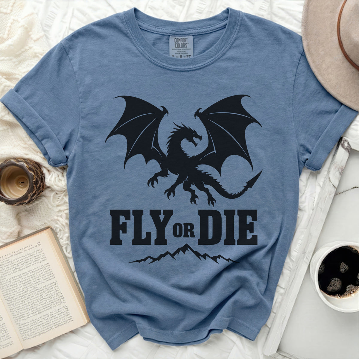 Blue t-shirt with black dragon and text "FLY OR DIE" above mountains.