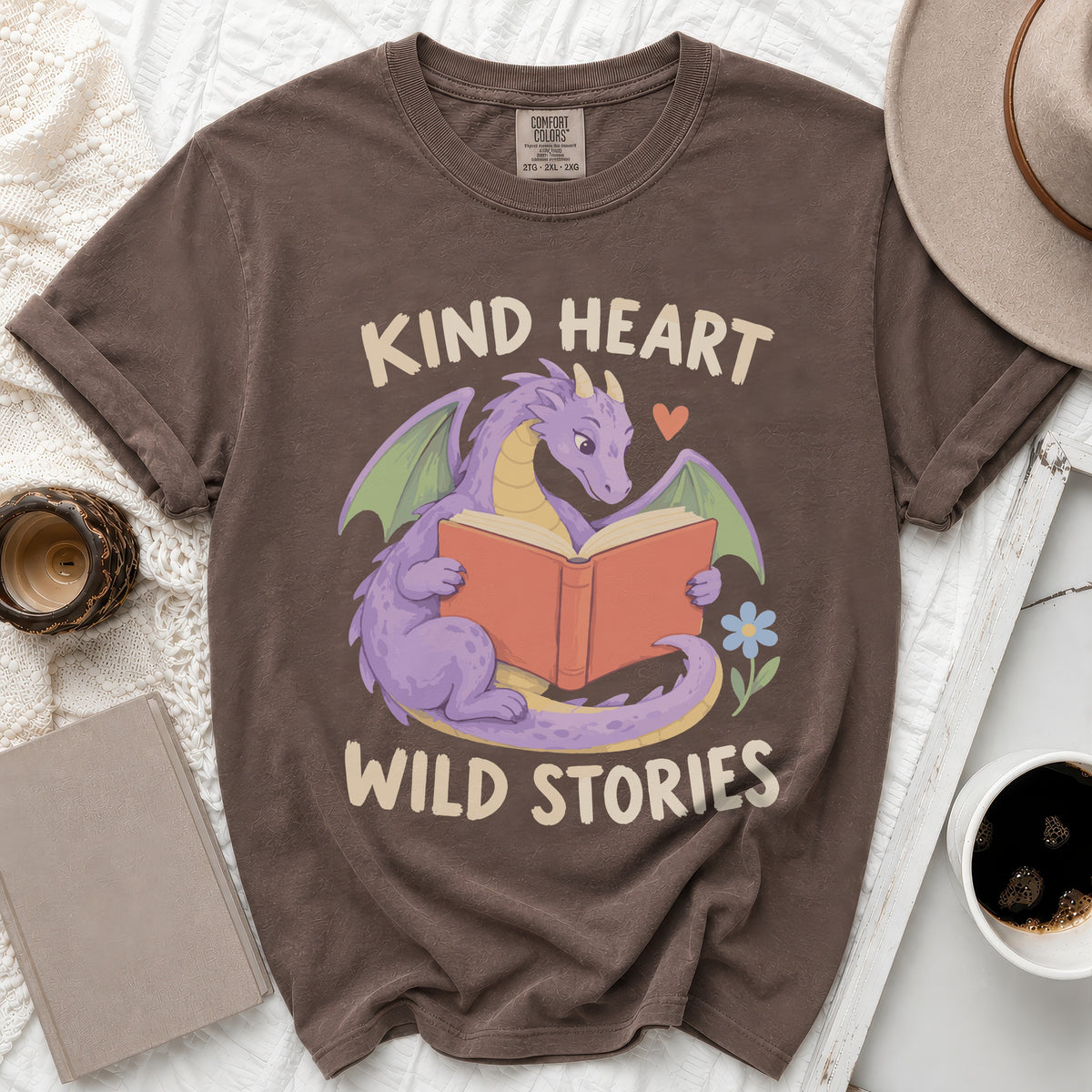 Brown t-shirt with purple dragon reading book, text "Kind Heart Wild Stories".