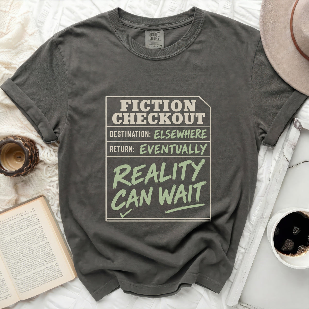 Charcoal grey t-shirt with "Fiction Checkout: Destination: Elsewhere, Return: Eventually, Reality Can Wait" graphic.