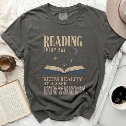 T-shirt with "Reading Every Day Keeps Reality At A Safe Distance" graphic.