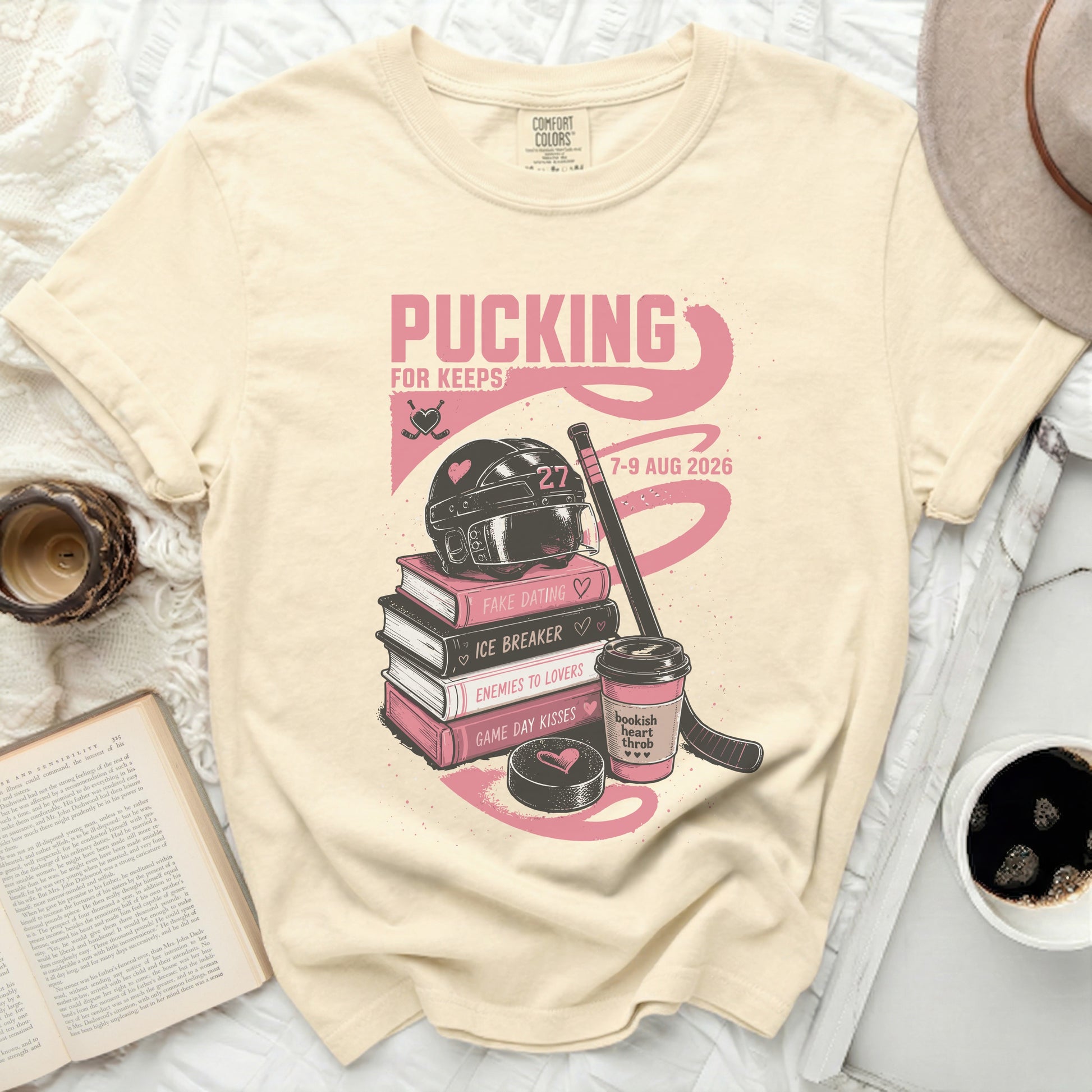 Cream t-shirt with "Pucking for Keeps" text, hockey gear, books, and heart graphics.