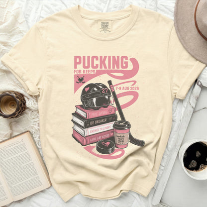 Cream t-shirt with "Pucking for Keeps" text, hockey gear, books, and heart graphics.