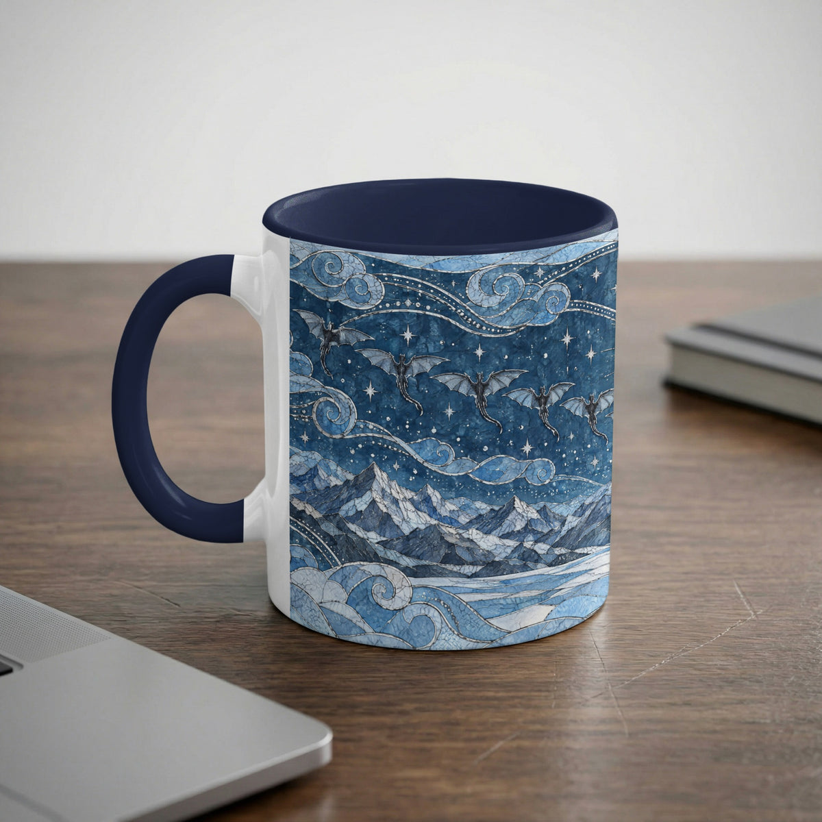 A white mug with a blue interior and handle features a fantasy mountain and dragon illustration in shades of blue.