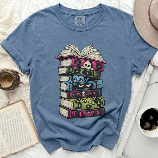 T-shirt with a stack of Halloween-themed books and cute characters.