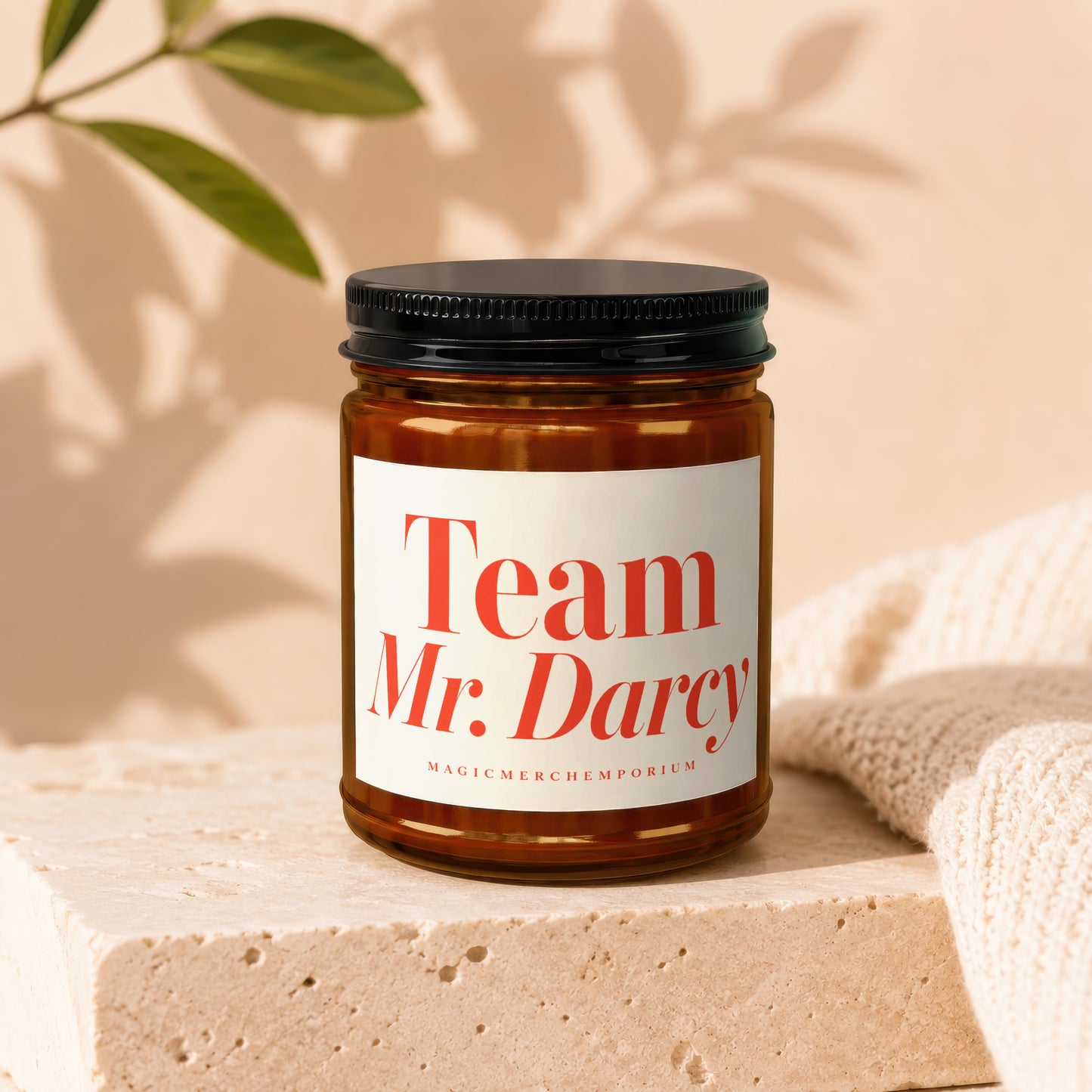 Amber glass jar candle with white label reading "Team Mr. Darcy" and "MAGICMERCH]EMPORIUM".