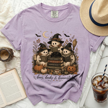Three cartoon ghosts read books around pumpkins and a candle, with the text "boos, books & broomsticks".