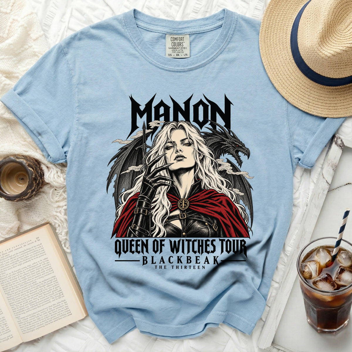 Light blue t-shirt with "MANON QUEEN OF WITCHES TOUR BLACKBEAK THE THIRTEEN" graphic.