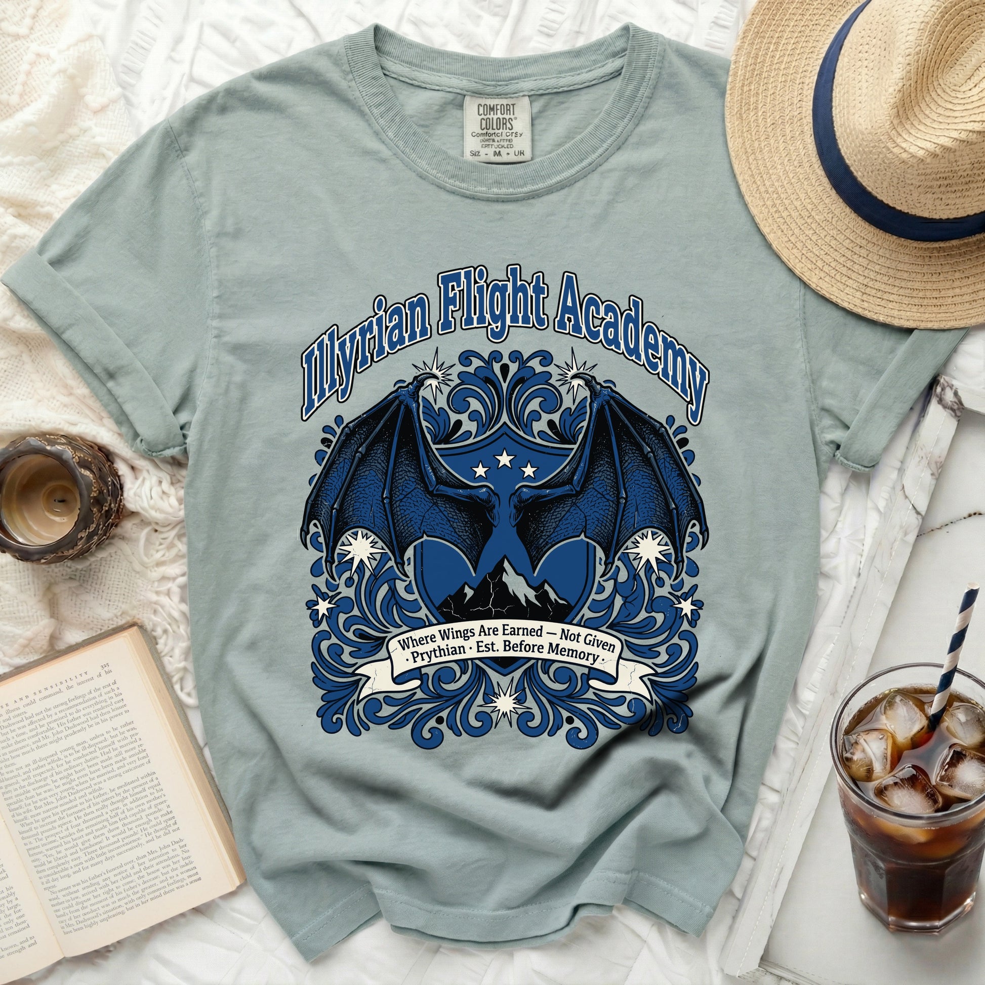 Pale blue t-shirt with blue dragon wings, mountains, and "Myrian Flight Academy" text.