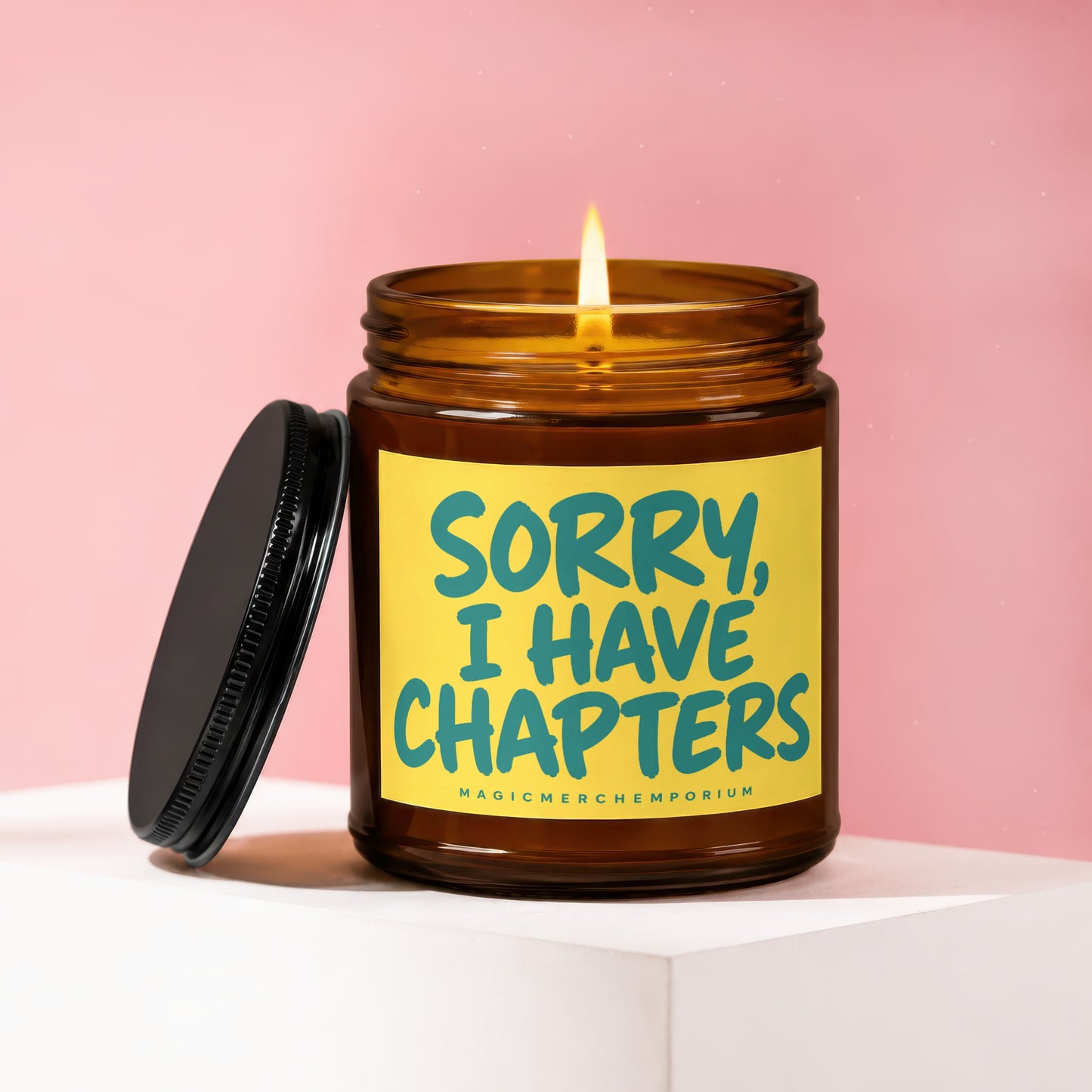 Amber glass candle with lit wick and black lid, featuring yellow label with turquoise text.