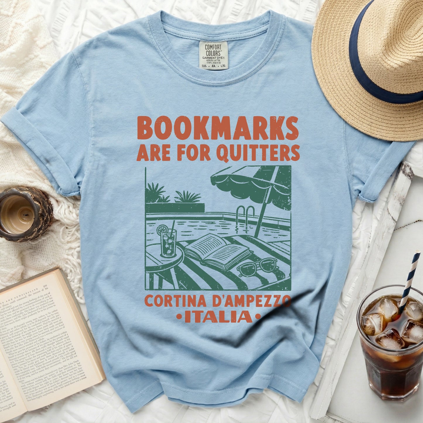 Light blue t-shirt with "Bookmarks are for quitters" and "Cortina d'Ampezzo Italia" text.