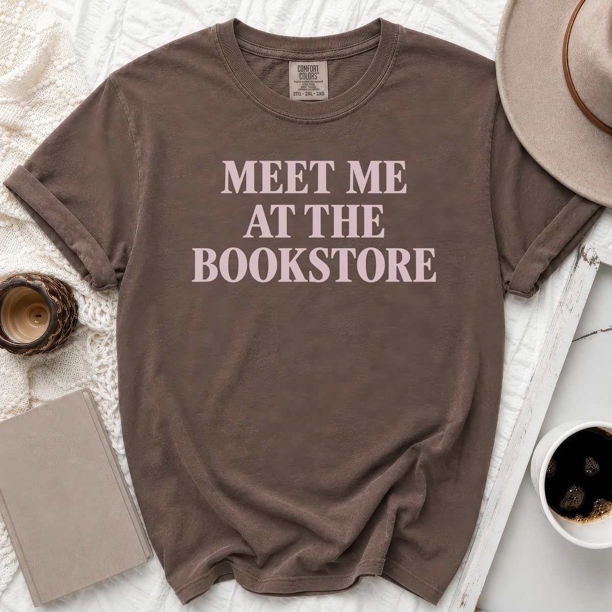 Brown t-shirt with "MEET ME AT THE BOOKSTORE" text in pink.