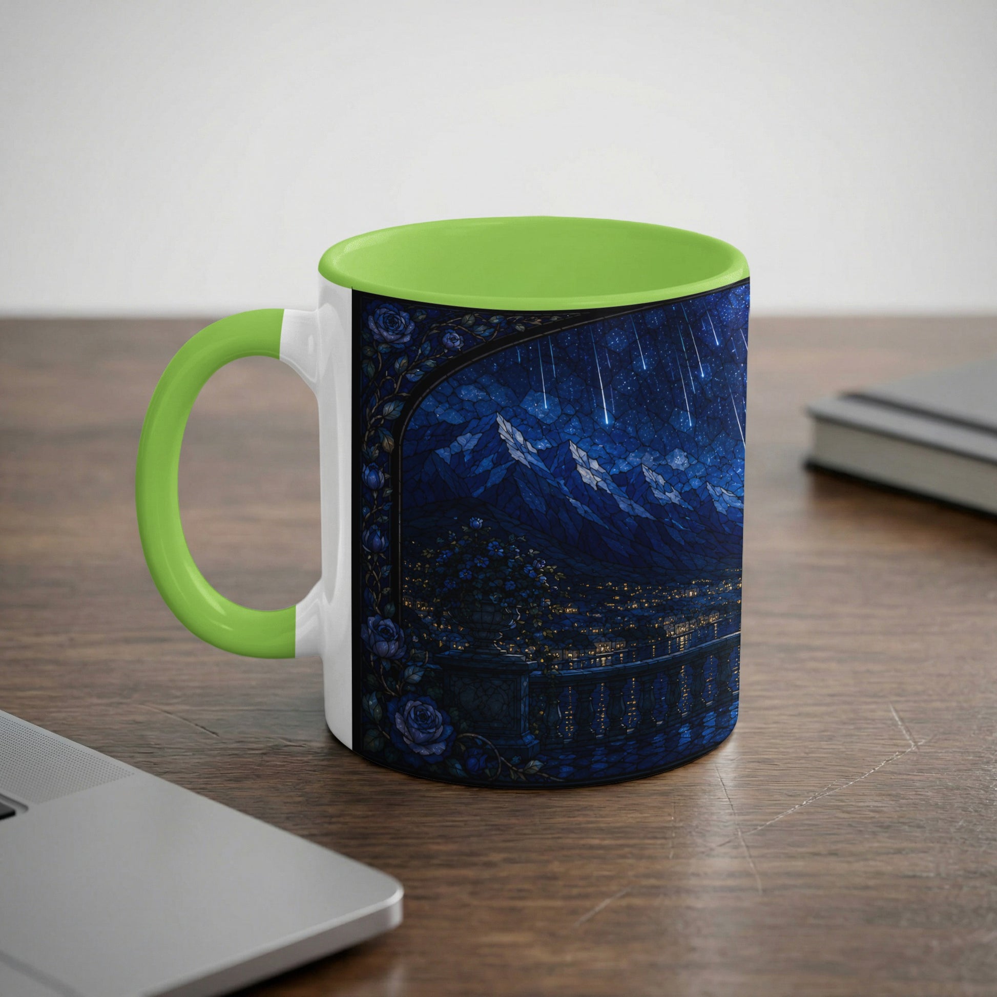 White mug with green handle featuring a dark blue stained-glass design of a starry night over mountains.