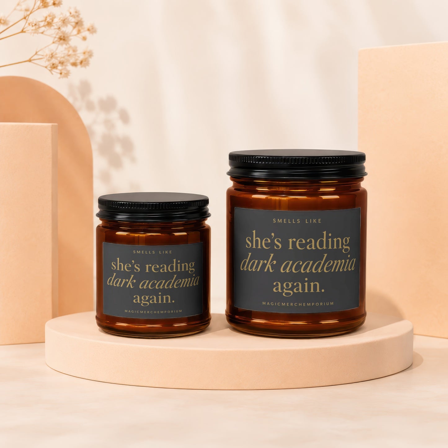 Two amber glass candles with black lids and dark labels reading "she's reading dark academia again."