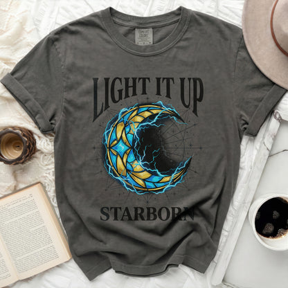 Dark t-shirt with "Light It Up Starborn" text and celestial crescent moon graphic.