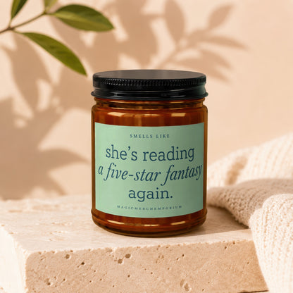 Candle with "She's reading a five-star fantasy again" text.