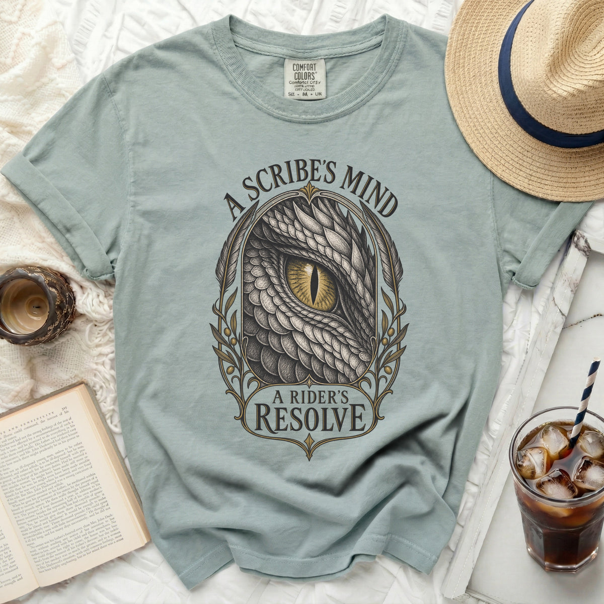 Light blue t-shirt with dragon eye graphic and text "A Scribe's Mind A Rider's Resolve".