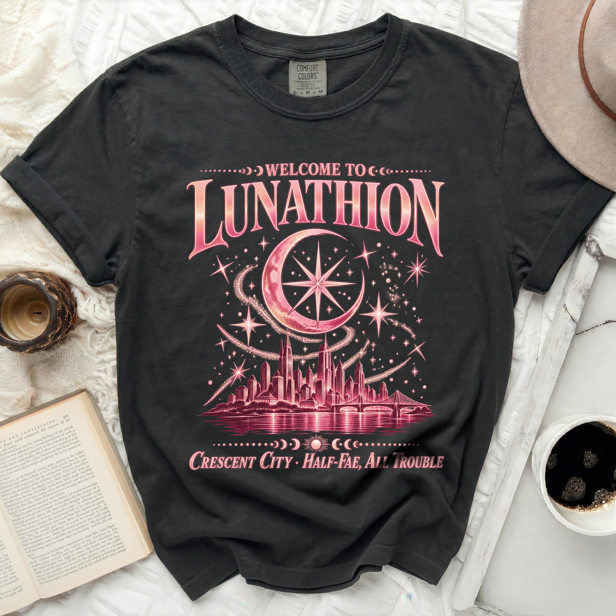 Black t-shirt with pink "Welcome to Lunathion Crescent City Half-Fae, All Trouble" graphic.
